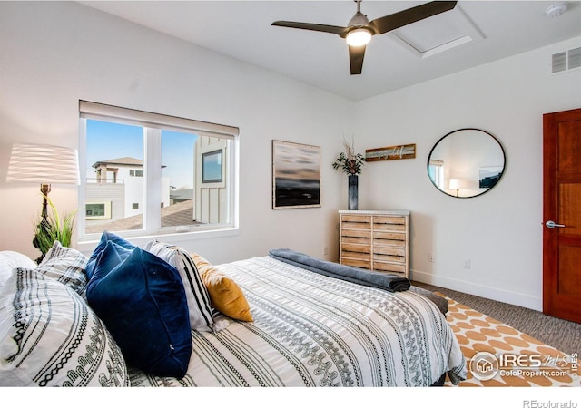 carpeted bedroom featuring attic access, baseboards, visible vents, and ceiling fan