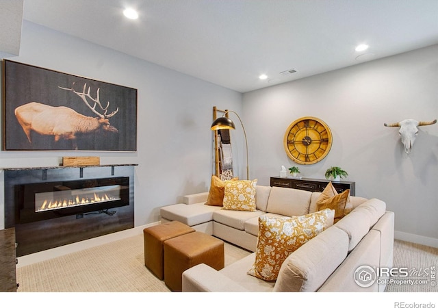 living area featuring visible vents, a glass covered fireplace, recessed lighting, carpet, and baseboards