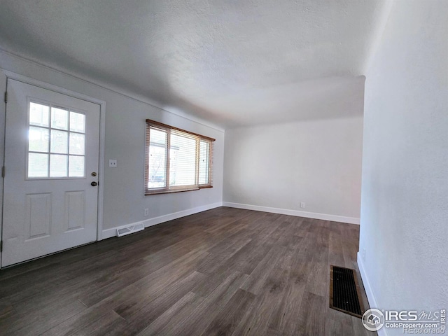 entryway with visible vents, baseboards, a textured ceiling, and dark wood finished floors