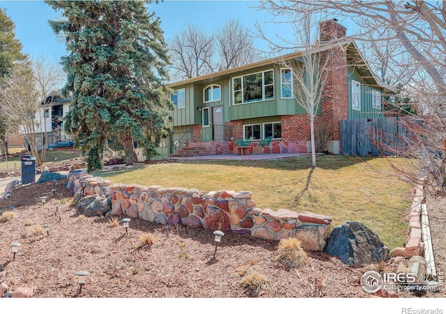 view of front of house featuring a front lawn, a patio, board and batten siding, brick siding, and a chimney