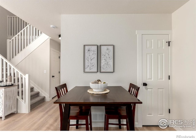 dining space featuring stairway and light wood-style floors