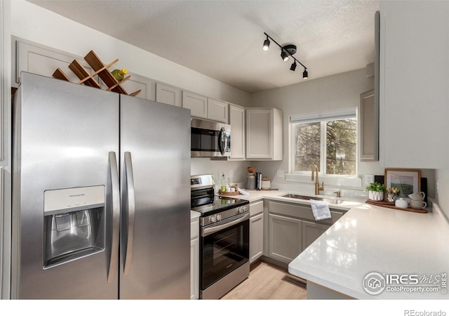 kitchen featuring a sink, light wood-style floors, appliances with stainless steel finishes, and light countertops