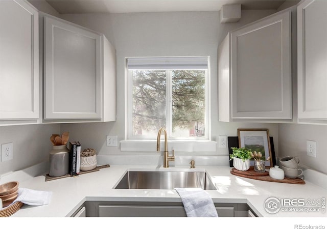 kitchen with light countertops, white cabinets, and a sink