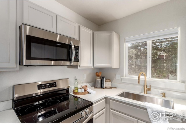 kitchen featuring a sink, stainless steel appliances, white cabinets, and light countertops