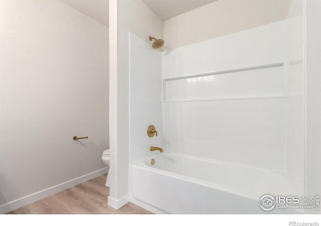 full bath with baseboards, toilet, wood finished floors, and shower / bathtub combination