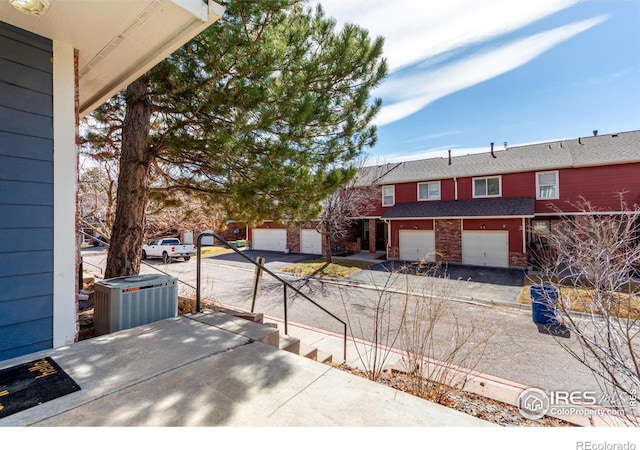 view of patio / terrace featuring central air condition unit, an attached garage, and driveway