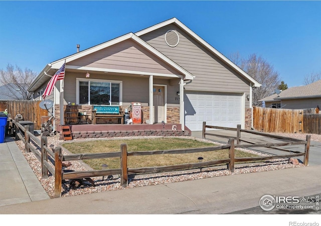 view of front of home with concrete driveway, a garage, stone siding, and a fenced front yard