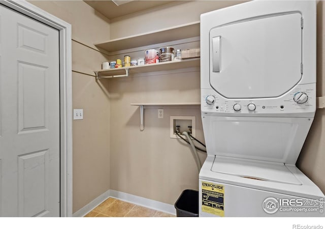 laundry room featuring baseboards, light tile patterned flooring, laundry area, and stacked washer / dryer