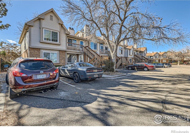 townhome / multi-family property featuring stairway, brick siding, a residential view, and uncovered parking