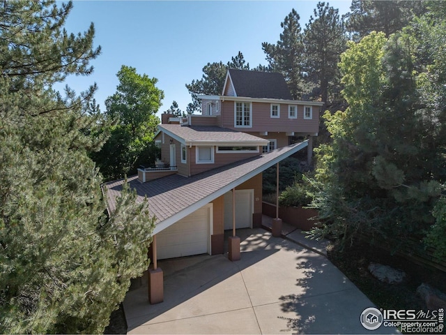 view of front of property with a shingled roof and concrete driveway