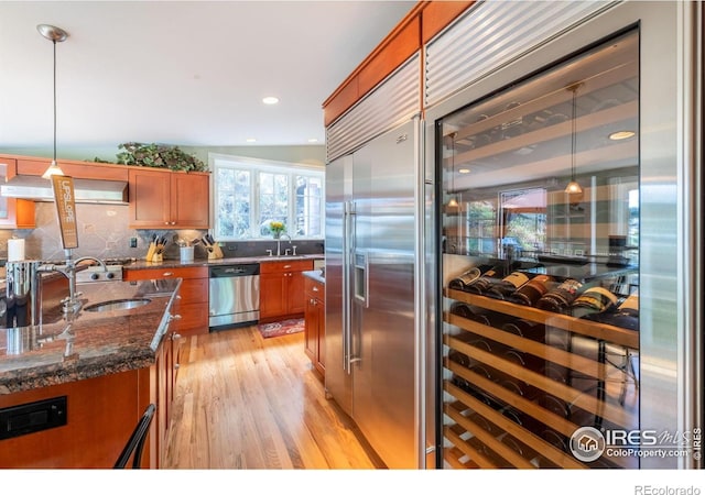 kitchen with brown cabinets, a sink, wine cooler, stainless steel appliances, and extractor fan