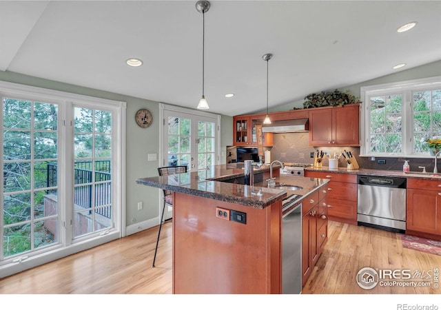 kitchen featuring brown cabinetry, ventilation hood, light wood finished floors, and dishwasher