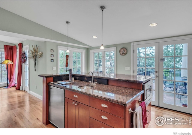 kitchen featuring fridge, brown cabinets, a sink, light wood-style flooring, and vaulted ceiling