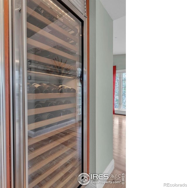 room details featuring baseboards, wine cooler, and wood finished floors
