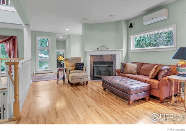 living area with an AC wall unit, a wealth of natural light, wood finished floors, and a fireplace