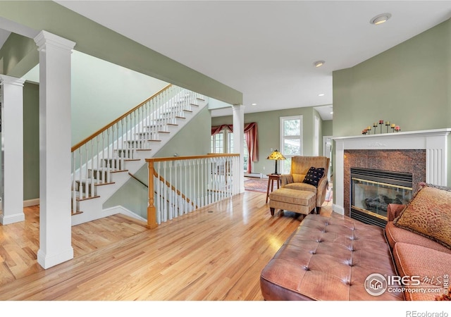 living area with ornate columns, baseboards, wood finished floors, and a tile fireplace