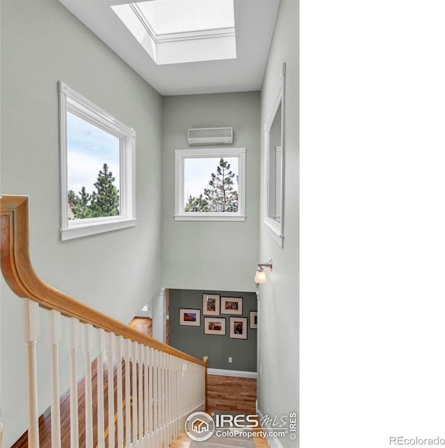 stairway featuring an AC wall unit, baseboards, and wood finished floors