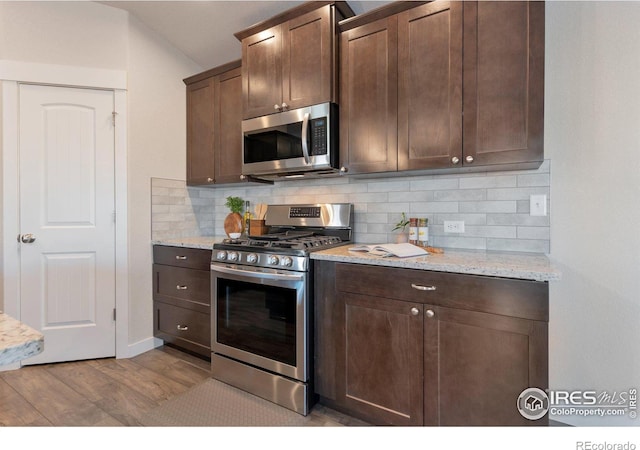 kitchen featuring backsplash, wood finished floors, appliances with stainless steel finishes, and dark brown cabinets