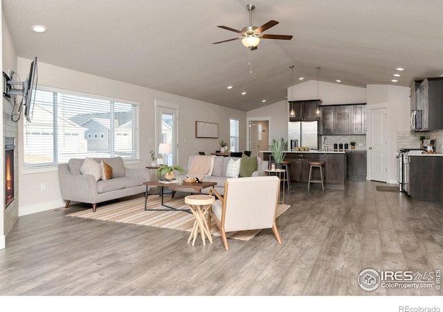 living room with recessed lighting, a ceiling fan, vaulted ceiling, and light wood finished floors