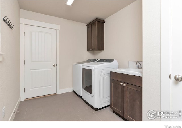 laundry room with a sink, cabinet space, baseboards, and washer and clothes dryer