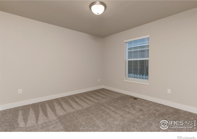 spare room with baseboards, carpet floors, and visible vents