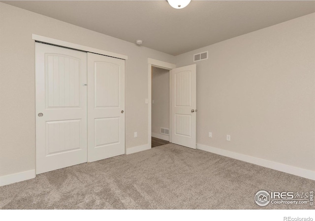 unfurnished bedroom with carpet flooring, visible vents, and a closet