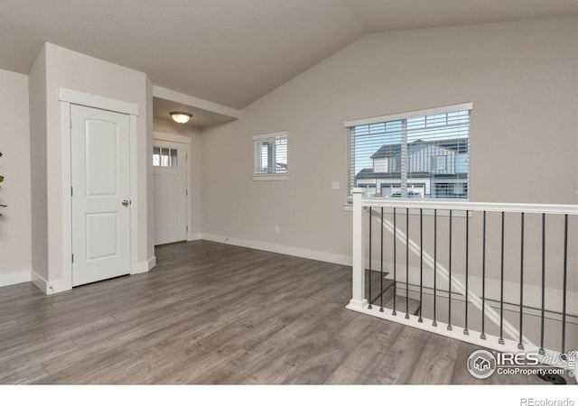 unfurnished room with baseboards, lofted ceiling, and wood finished floors