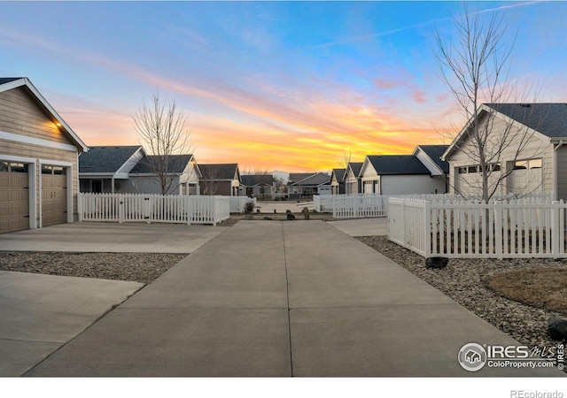 view of patio / terrace with a fenced front yard, a residential view, and concrete driveway