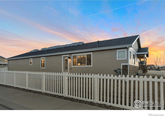 exterior space with a fenced front yard and a shingled roof