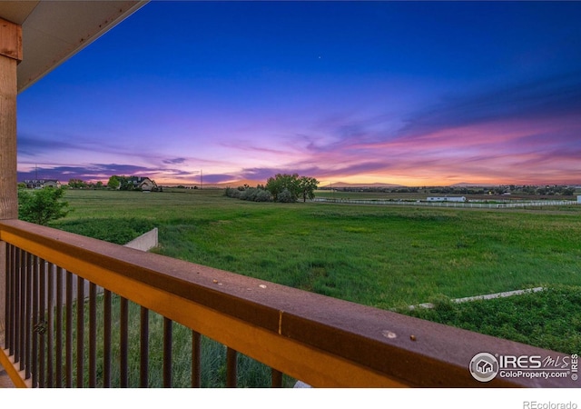 balcony at dusk featuring a rural view