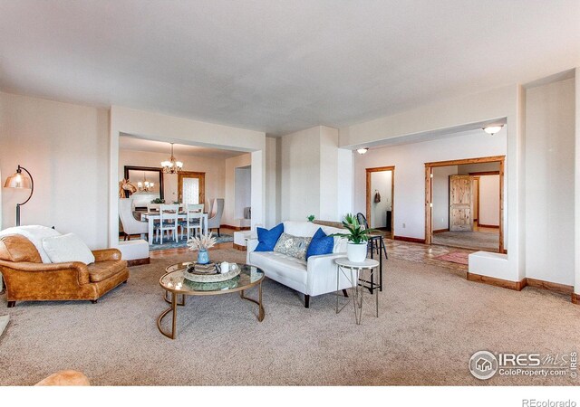 living room with a notable chandelier, baseboards, and carpet