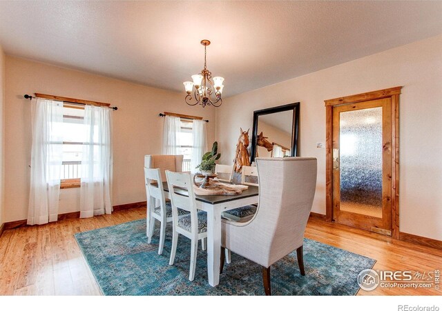 dining area with a notable chandelier, baseboards, and wood finished floors