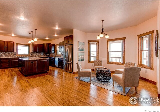 kitchen featuring a kitchen island, tasteful backsplash, appliances with stainless steel finishes, and light wood finished floors