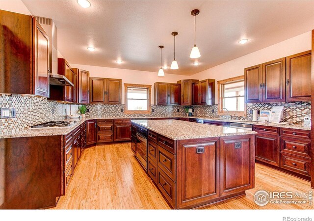 kitchen featuring a center island, light wood-type flooring, a wealth of natural light, and stainless steel appliances