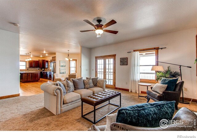 living room featuring baseboards, french doors, a textured ceiling, and a ceiling fan