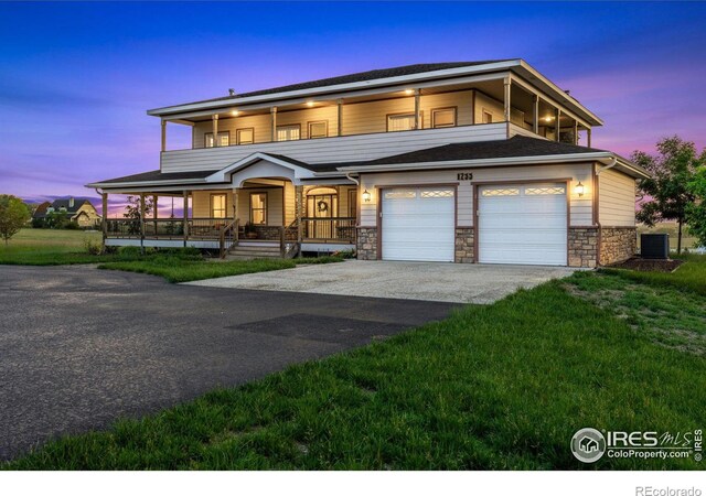 view of front of home with driveway, central air condition unit, covered porch, and stone siding