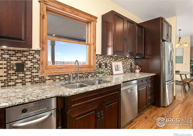 kitchen with dark brown cabinetry, light wood finished floors, appliances with stainless steel finishes, and a sink