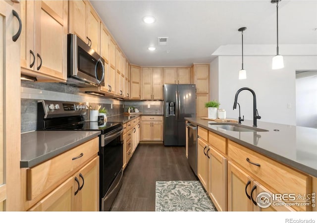 kitchen with dark countertops, light brown cabinetry, decorative backsplash, stainless steel appliances, and a sink