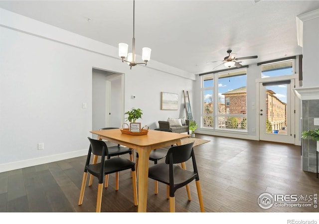 dining area with dark wood-type flooring, ceiling fan with notable chandelier, baseboards, and expansive windows