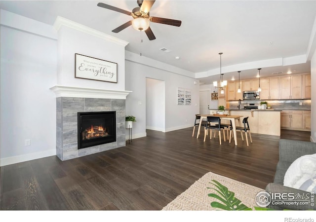 living room featuring a tiled fireplace, dark wood-type flooring, baseboards, and visible vents