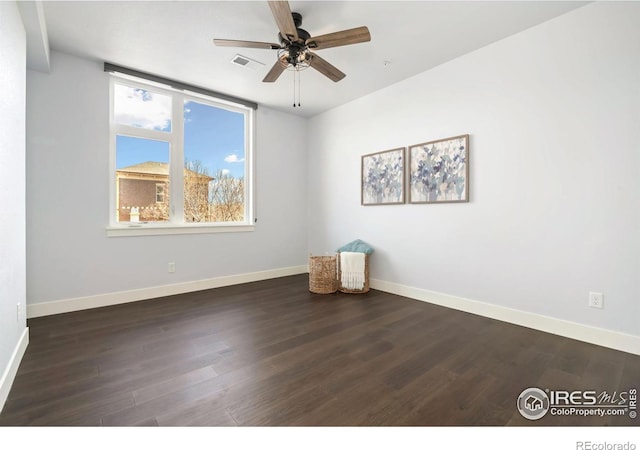 unfurnished room featuring dark wood finished floors, visible vents, a ceiling fan, and baseboards