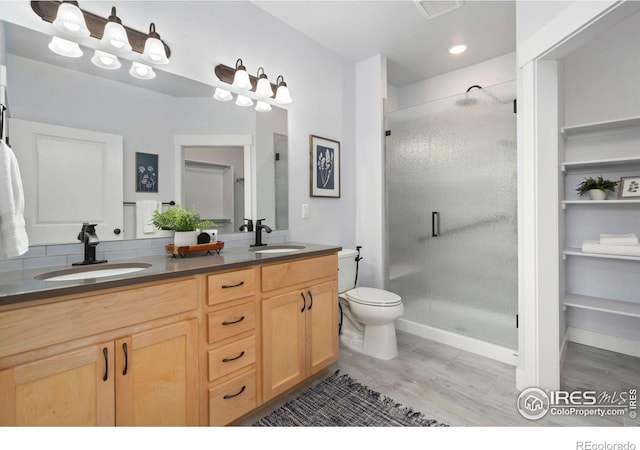 bathroom with double vanity, a shower stall, toilet, and a sink