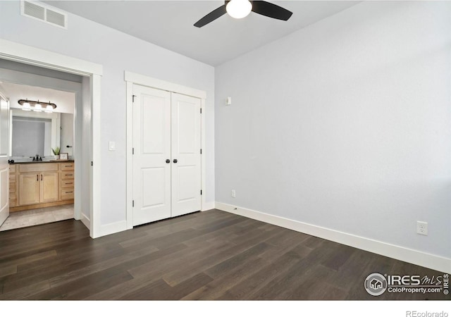 unfurnished bedroom with visible vents, baseboards, a closet, and dark wood-style floors