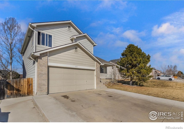 traditional home featuring a garage, brick siding, concrete driveway, and fence