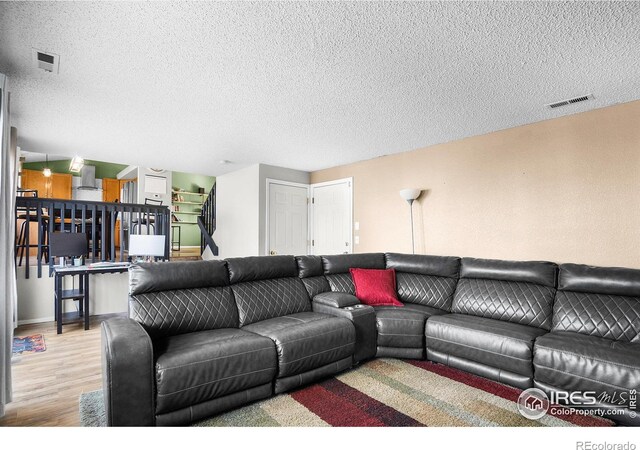 living area featuring visible vents, a textured ceiling, and wood finished floors