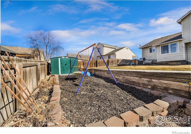 view of playground featuring a storage unit, a fenced backyard, and an outdoor structure