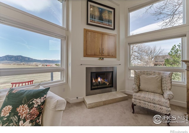 sitting room featuring a glass covered fireplace, a mountain view, carpet flooring, and baseboards