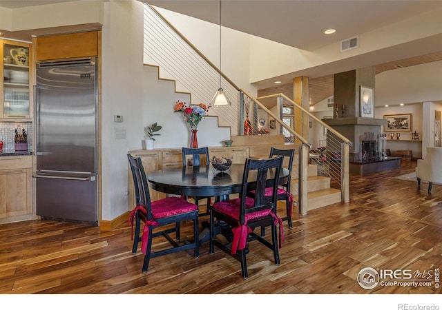 dining space with stairway, wood finished floors, visible vents, and a towering ceiling