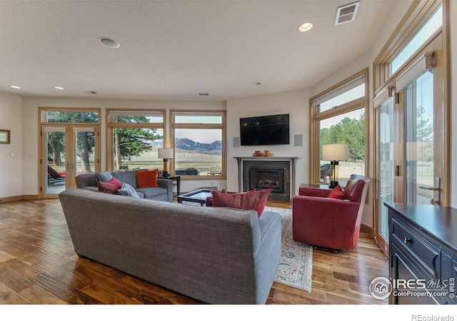 living room featuring visible vents, wood finished floors, recessed lighting, french doors, and a fireplace