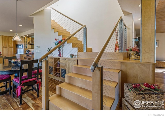 stairway with recessed lighting and wood finished floors